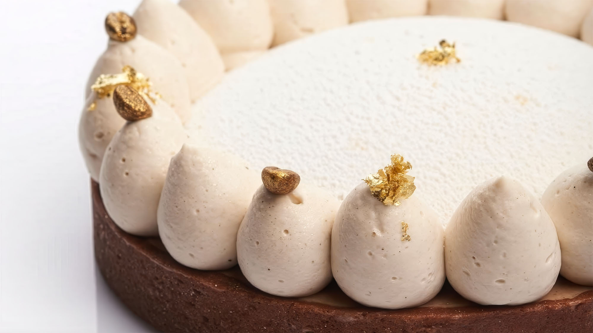 Dessert moderno di alta pasticceria con crema mousse e bavaresi su base di frolla, decorato con dettagli in foglia d’oro